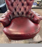 Chesterfield-Sessel nach der Aufarbeitung: tiefrotes, geschlossenes Leder mit sauberer Knopfheftung.